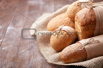 Fresh hot bread in a linen towel on a brown wooden table. free space for writing text. menu. advertising