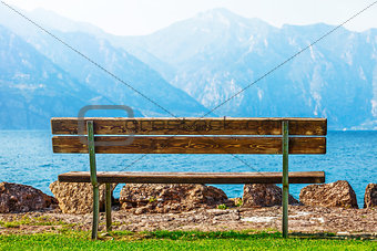 Wooden bench at coast of lake with blue mountains