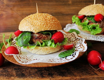 Homemade traditional burgers with beef,radish,lettuce, served on wooden background.
