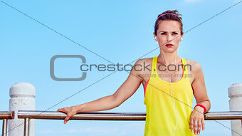 healthy woman in fitness outfit listening to music at embankment