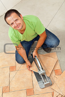 Man laying ceramic floor tiles - cutting one piece
