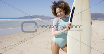 Smiling female standing with surfboard