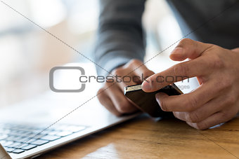 Man hands scrolling cell phone in office