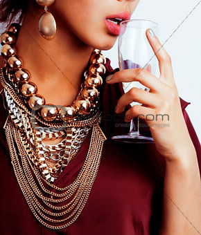 young african-american woman drinking champagne, holding glass, wearing lot of golden jewelry