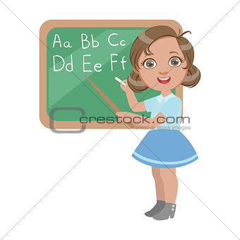 Cute little girl standing near the blackboard and writing letters of the English alphabet, a colorful character isolated on a white background