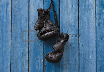 Black vintage boxing gloves hanging on an old rusty nail 