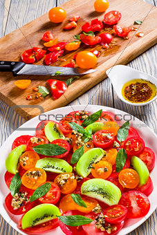 tomato, kiwi fruit and cheese brie salad decorated with mint lea