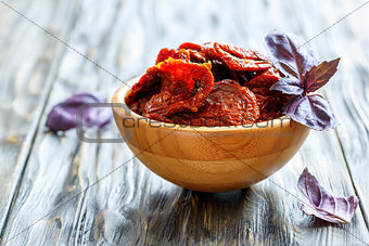 Sun-dried tomatoes and basil leaves in a wooden bowl.ÑÑ