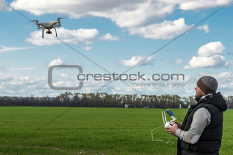 man operating of flying drone quadrocopter at the green field