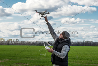 man holding of flying drone quadrocopter at the green field