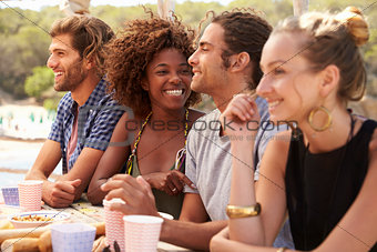 Four friends at a table by the sea, couple kissing, close up