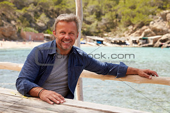 Middle aged Caucasian man sitting at a table on a jetty