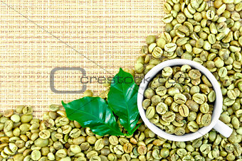 Coffee green grains with cup on yellow woven fabric