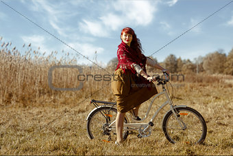 Pretty girl riding bicycle in field