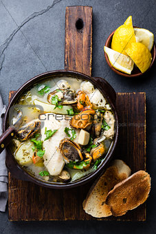 Seafood fish soup in clay bowls served with lemon and coriander. Top view, copy space