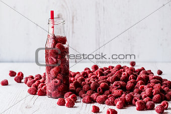 detox water in bottle with raspberry on white wooden background