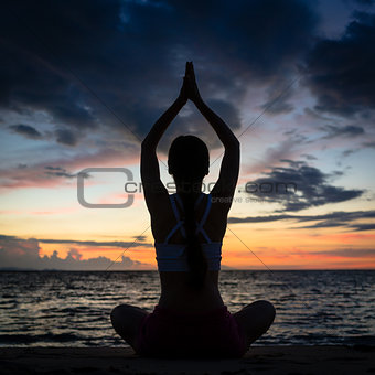 Fit woman sitting in lotus position while practicing yoga on the