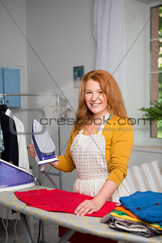 Foxy haired female at home ironing.