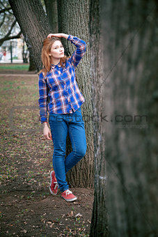 Portrait of a beautiful girl. smiling, posing on camera. in a blue shirt in a cage. Against the background of the autumn park
