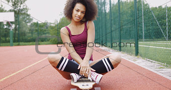Charming model sitting on skateboard