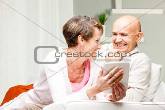 Husband and wife chuckling over a tablet pc