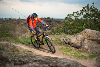 Cyclist in Red Riding the Bike on Autumn Rocky Trail. Extreme Sport and Enduro Biking Concept.