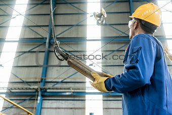 Skilled Asian worker controlling industrial hook