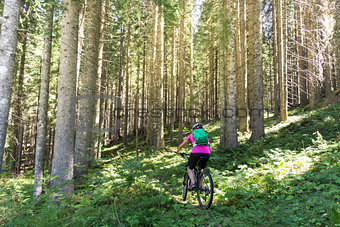 Active sporty woman riding mountain bike on forest trail .