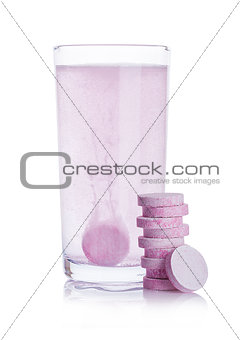 Glass with sparkling medical vitamin pills on white
