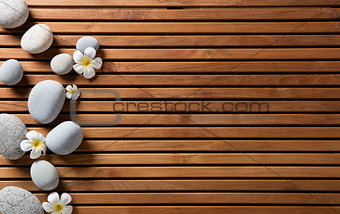 zen pebbles and spa flowers set on hammam wooden board