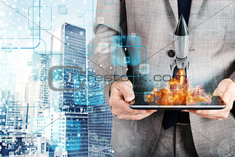 Businessman launches rocket from a tablet. concept of company startup