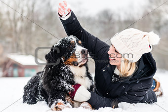 Woman hugging her dog in the snow