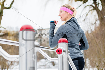 Young woman training her legs on fitness path on winter day