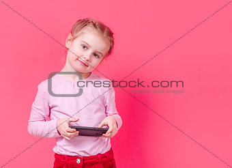 Adorable girl using smartphone over pink background