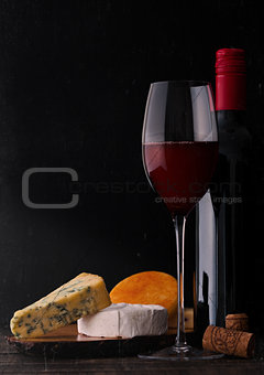 Bottle and glass of red wine with cheese selection