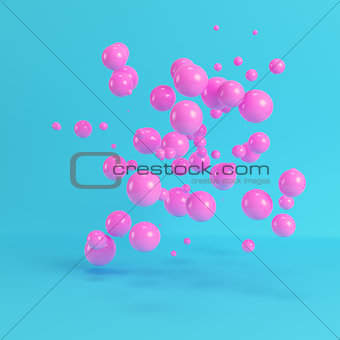 Pink flying spheres on bright blue background in pastel colors