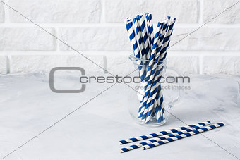Glass jug with striped blue drinking straws brick wall backgroun