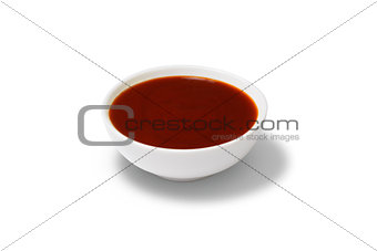 Red sauce in a gravy boat on white background
