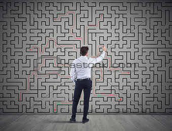 Businessman draws the solution of a labyrinth. Concept of problem solving