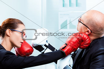 businesswoman hitting businessman's face with a punch