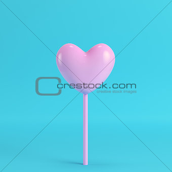 Pink heart on a stick on bright blue background