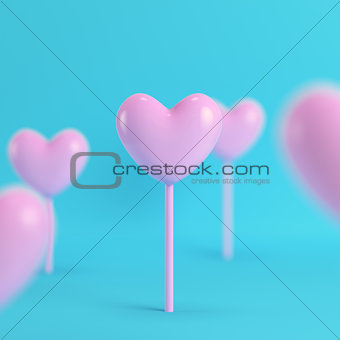 Pink hearts on a stick on bright blue background in pastel color