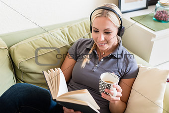 Relaxed young woman reading a book and listening to music