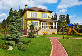 Exterior of luxury home with green yard and children playground