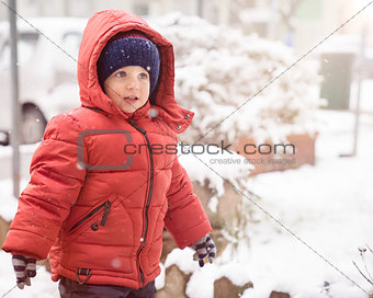 Baby boy with red jacket and hat while snows