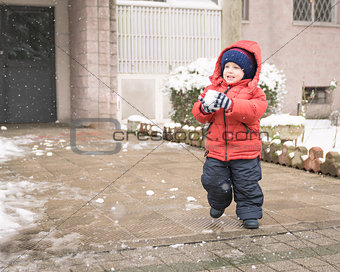Infant runs with a snowball in his hands