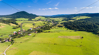 Road, village and mountain summer landscape from above - drone view
