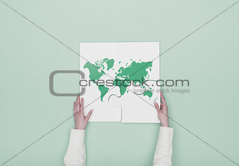 Woman completing a puzzle with a world map