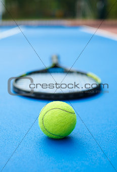 Yellow ball on tennis racket background.