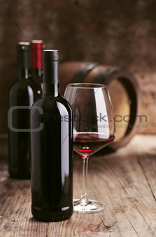 Wine bottles with barrel on wooden background